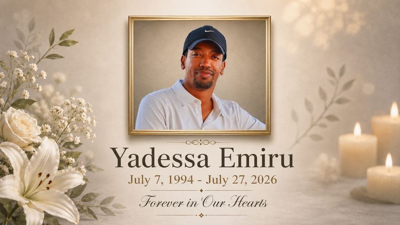 A memorial card for Yadessa Emiru — a framed portrait of him smiling in a black cap and white polo, surrounded by white lilies and candlelight, above the dates July 7, 1994 – July 27, 2026 and the words “Forever in Our Hearts.”